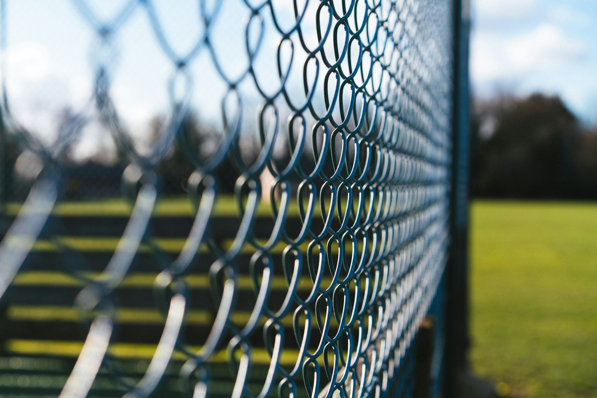 a close up of a metal fence with grass in the background